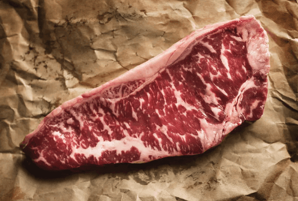 Bife de corte de gado Wagyu sobre uma folha de papelote.